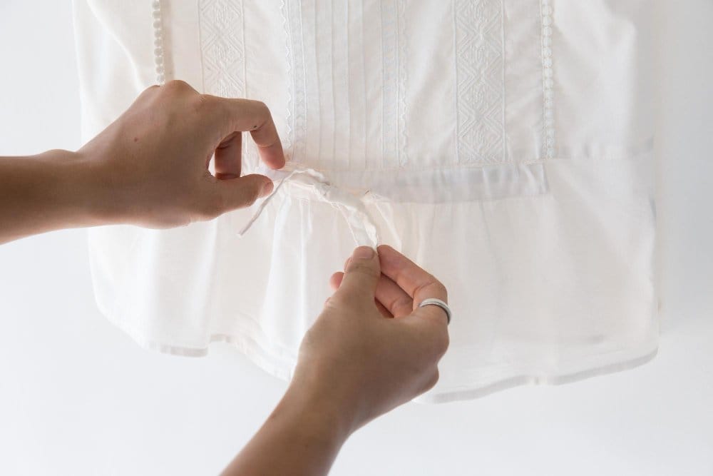 Hands gently handling white rayon chiffon fabric showing delicate care and garment maintenance
