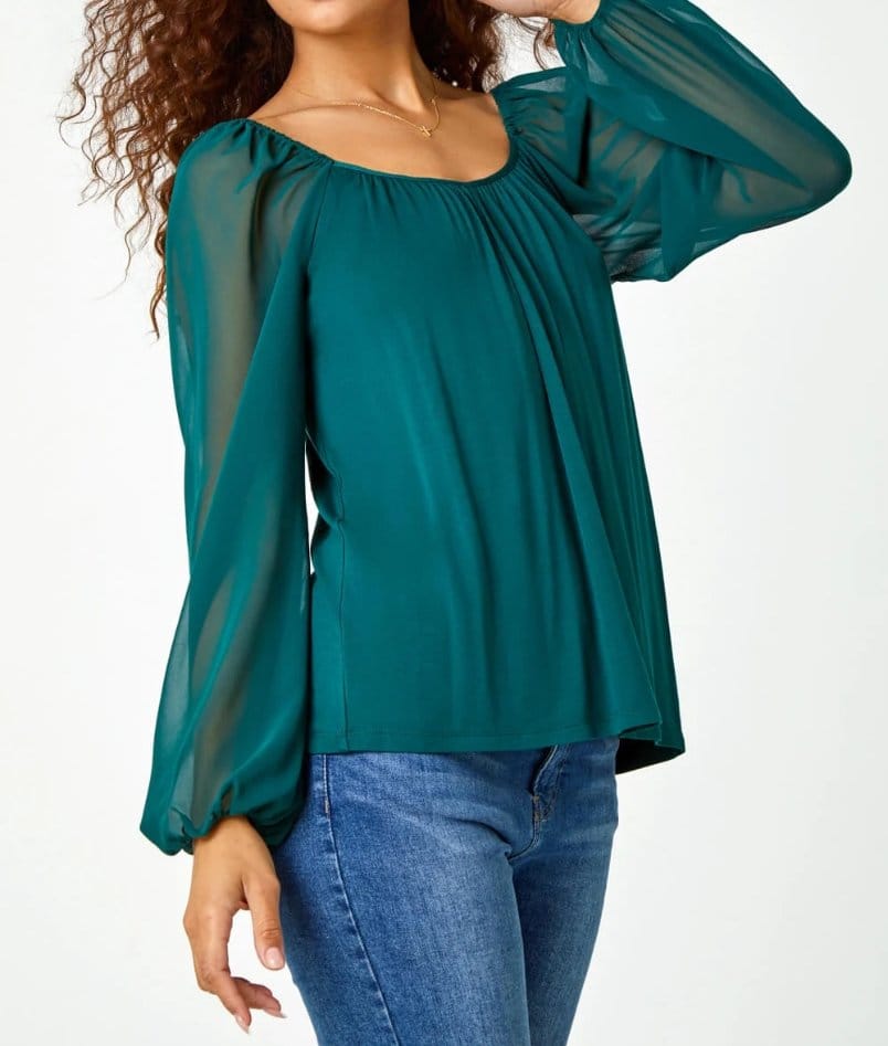 Teal blouse with sheer stretch chiffon sleeves paired with jeans