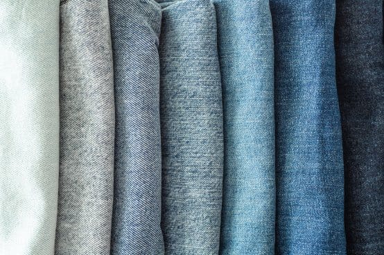 Vertical lineup of fabric samples in various blue and neutral shades representing common cotton denim terms and finishes.
