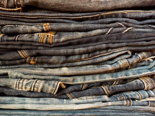Stack of folded jeans in different washes representing common raw denim terms, finishes, and construction details.