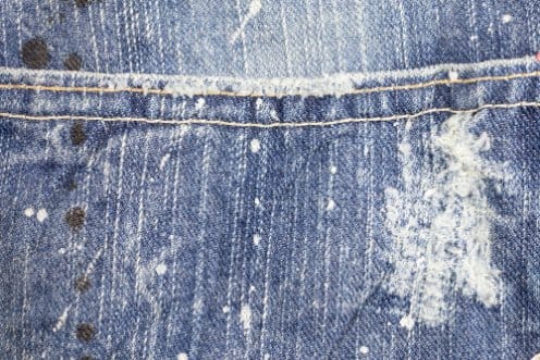 Close-up of blue denim with faded curved seat-area wear marks known as monkey wash effects.