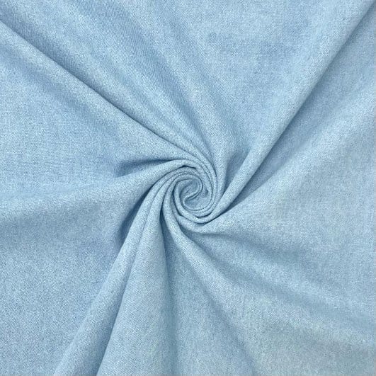 Light blue washed denim fabric in soft spiral folds showing a smooth finish and faded appearance.