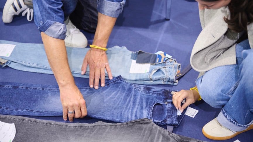 Designers reviewing denim samples and measurements while planning production with supplier