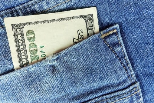 Dollar bill inside denim pocket representing cost and pricing of colored denim production