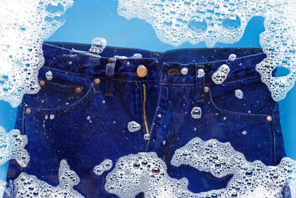 Denim jeans submerged in water during fabric testing for colorfastness and durability