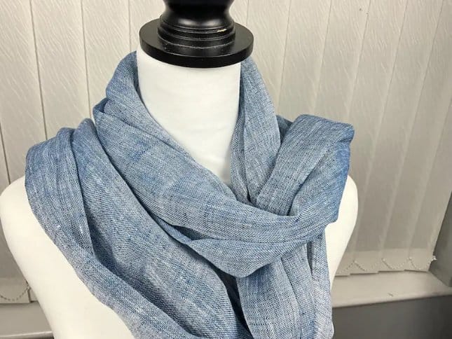 Light blue chambray scarf draped elegantly on a mannequin, showcasing the fabric's soft texture, lightweight feel, and versatile styling potential.