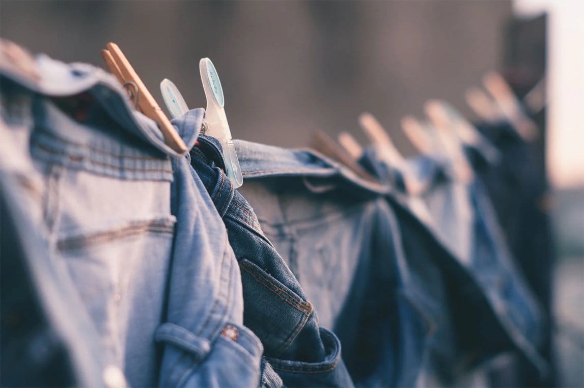 Caring for Your DIY Acid Washed Piece denim jeans hanging on clothesline with clothespins drying naturally after washing