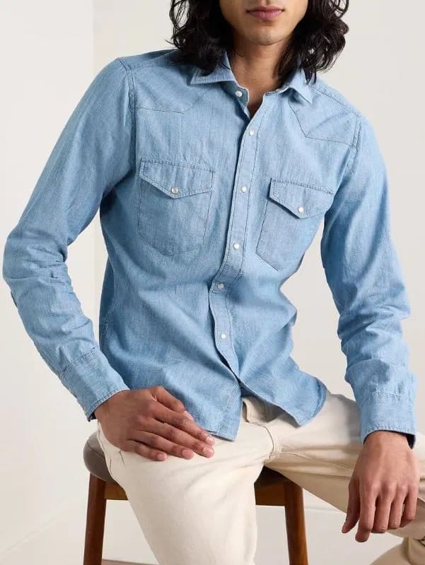 Man wearing a light blue chambray shirt with cream pants, demonstrating a classic smart-casual chambray outfit formula.