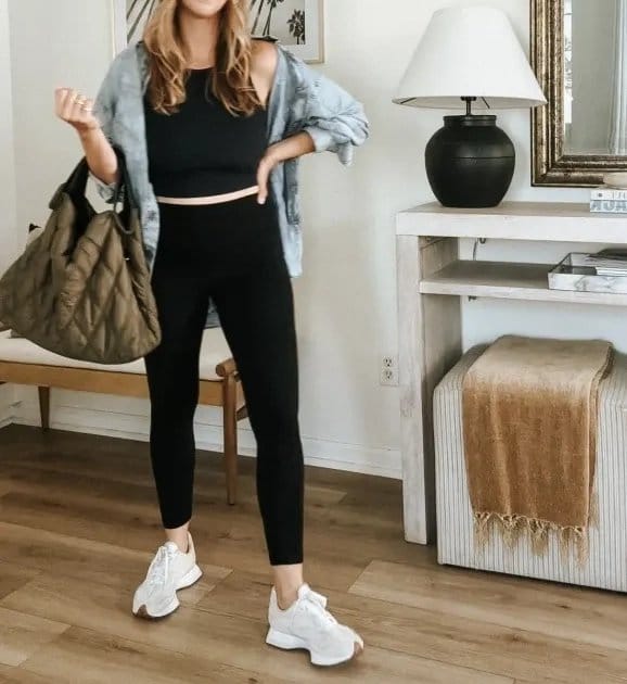 Woman wearing a chambray overshirt layered over a black outfit with sneakers, demonstrating a simple and stylish chambray outfit formula.
