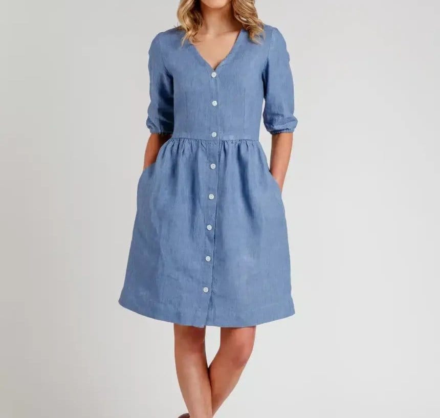 Woman wearing a light blue chambray dress with button front design, demonstrating a popular clothing use for chambray fabric.