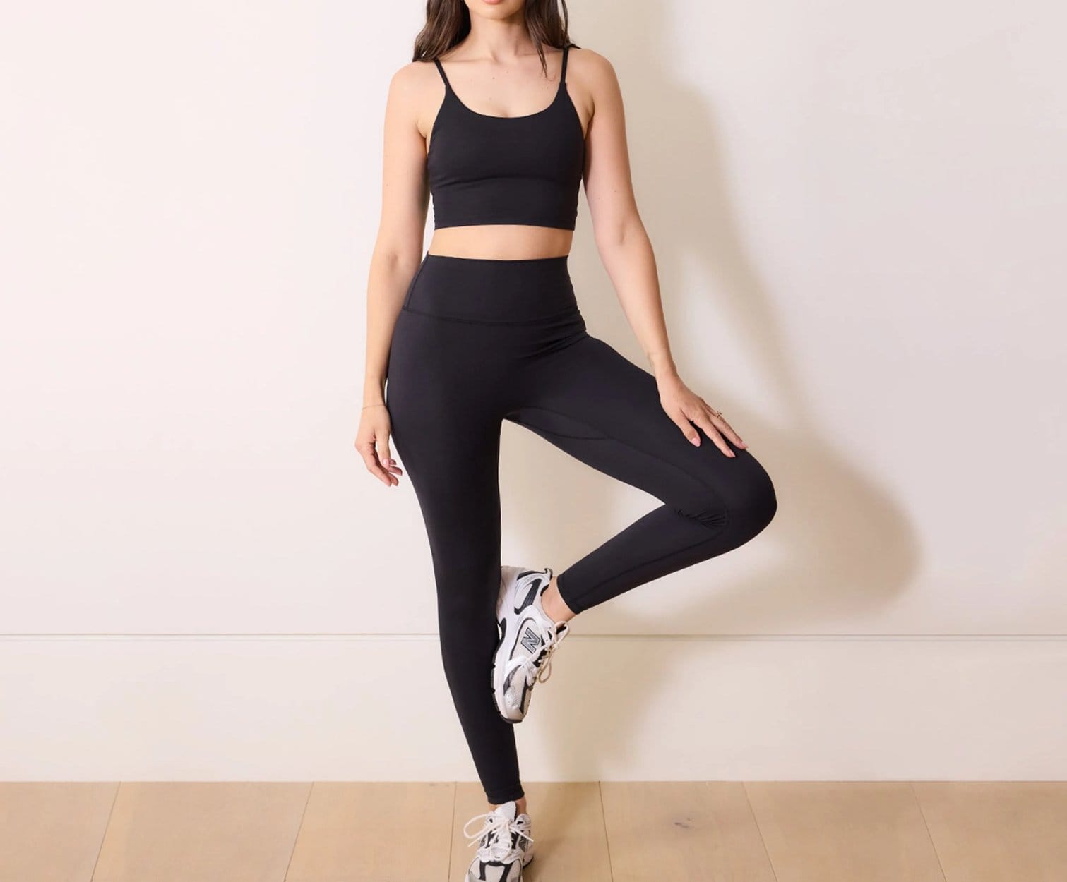 Woman wearing black spandex activewear set with high waist leggings and sports crop top.