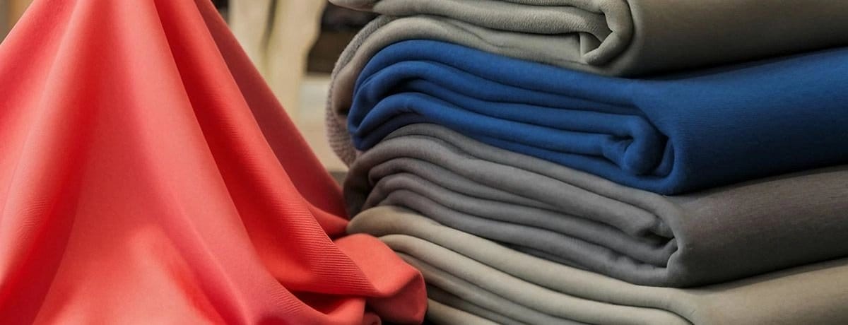Folded nylon spandex fabrics in various colours demonstrating the combination of nylon strength and spandex elasticity.