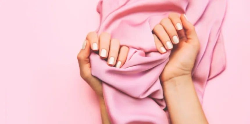 Hands holding soft pink spandex fabric to demonstrate texture and comfort.