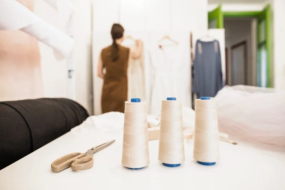 Sewing workspace with thread spools, scissors and fabric materials prepared for nylon sewing projects at home.