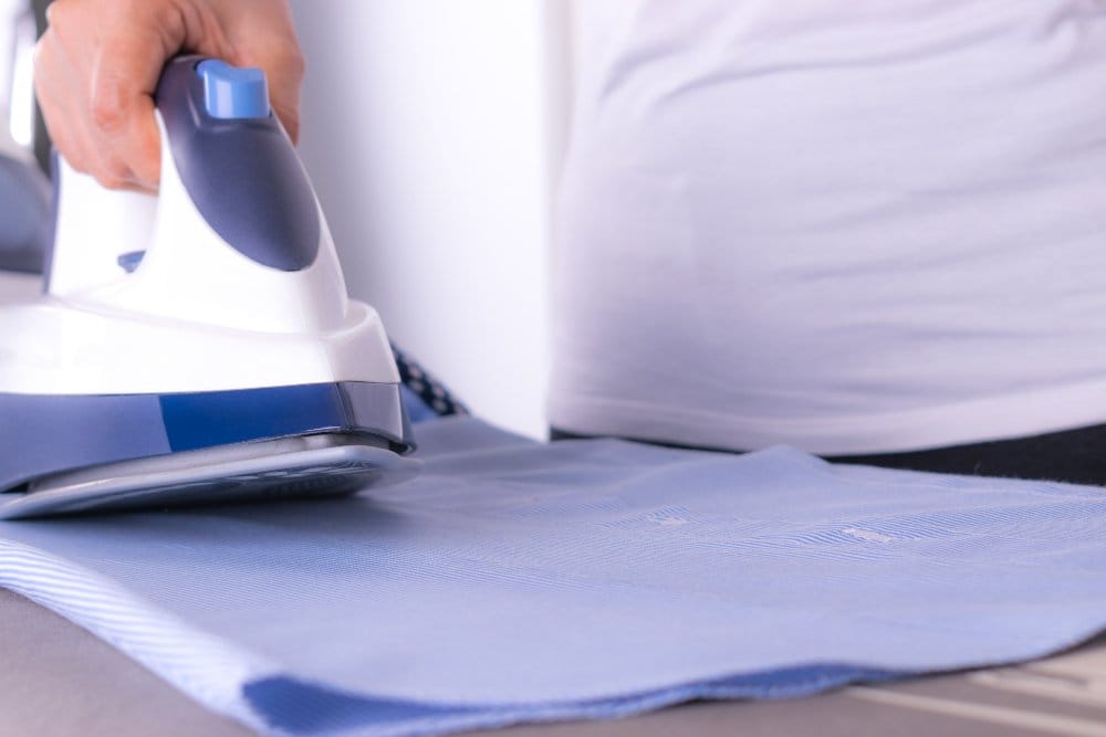 Iron pressing nylon fabric at a low temperature to remove wrinkles while preventing heat damage.