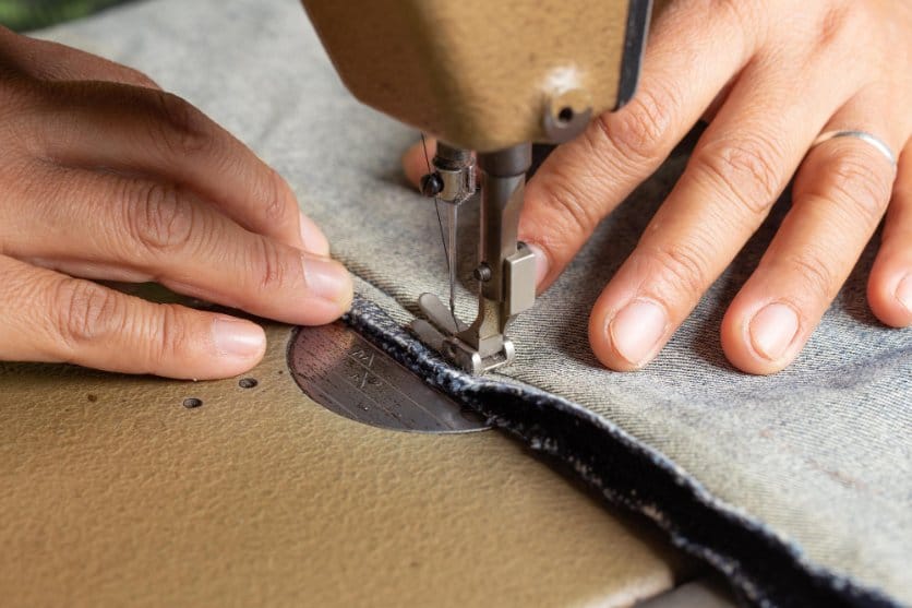 Close-up of a sewing machine stitching fabric edges to create durable seams and prevent fraying.