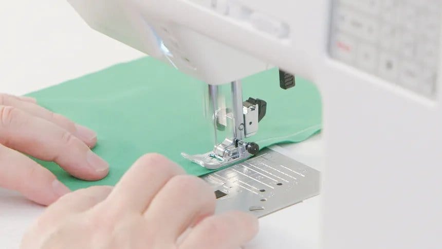 Sewing machine stitching stretch fabric during garment construction.