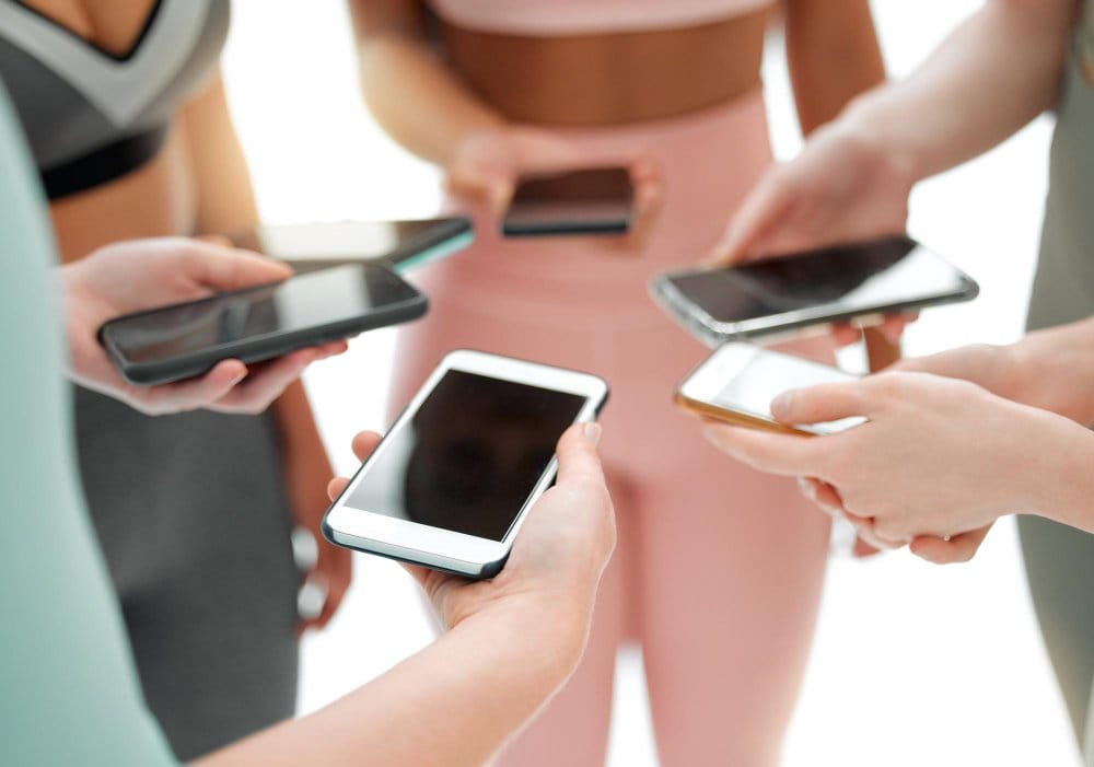 People using smartphones while wearing modern activewear and stretch clothing.