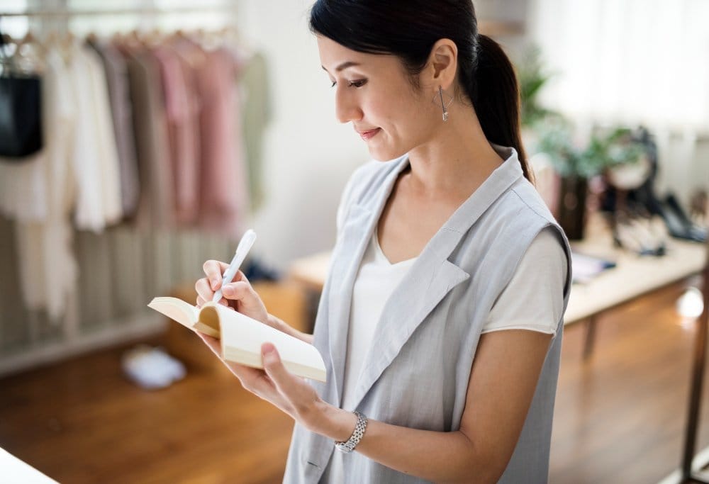 Retail professional taking notes while creating compelling product descriptions for fashion and nylon fabric products.