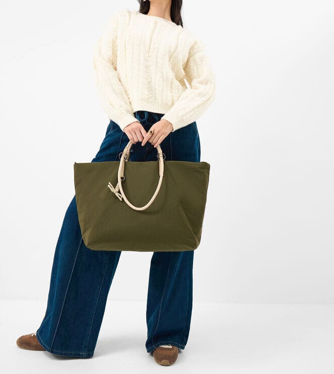 Woman carrying a large nylon tote bag designed for durability, lightweight performance and everyday practicality.