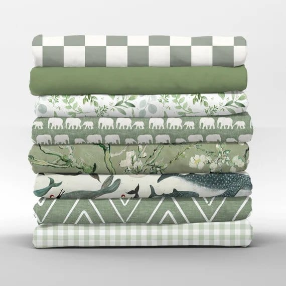 Stack of green and white patterned quilting cotton fabrics featuring checks, leaves, florals and geometric designs.