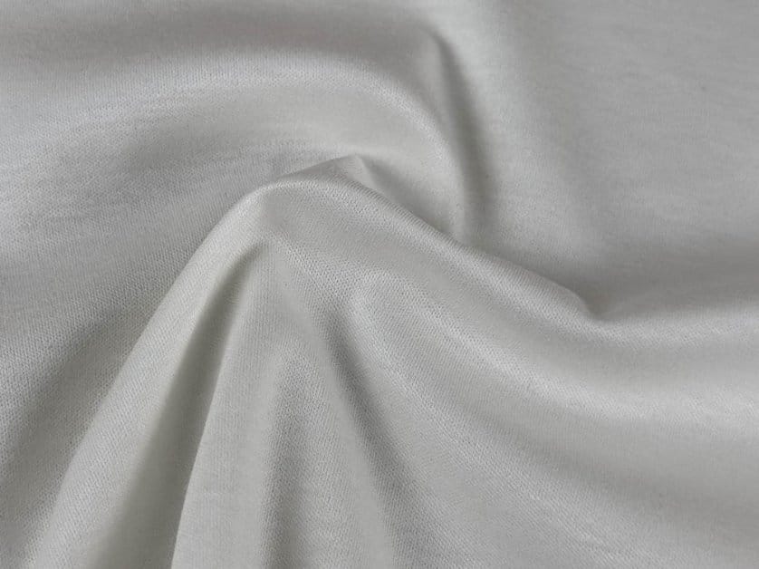 Close-up of smooth white mercerized cotton fabric draped in soft folds, showing its fine texture and subtle lustrous finish.